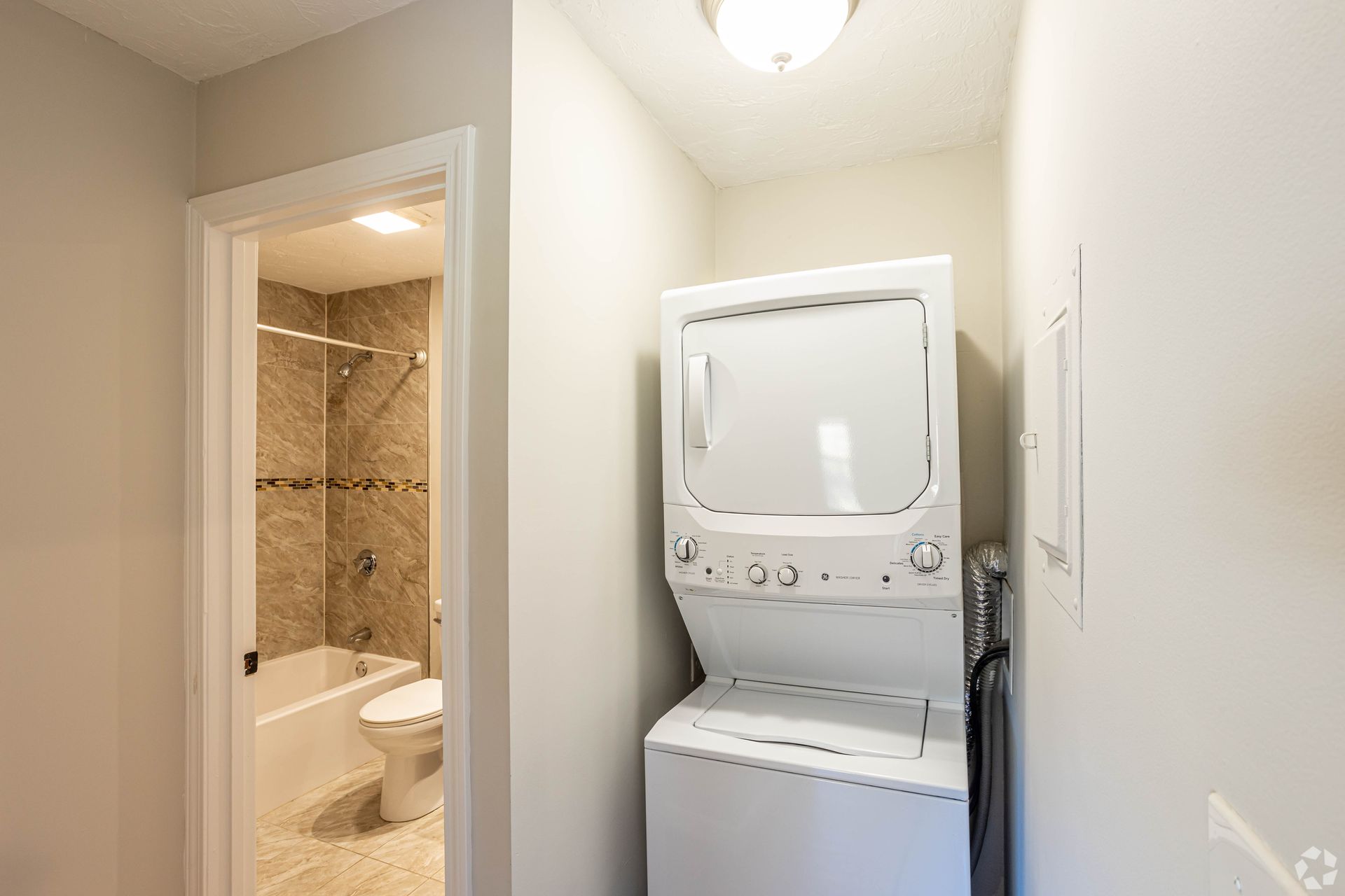 In-unit stacked washer and dryer next to bathroom at Waltham Overlook Apartments in Waltham, MA
