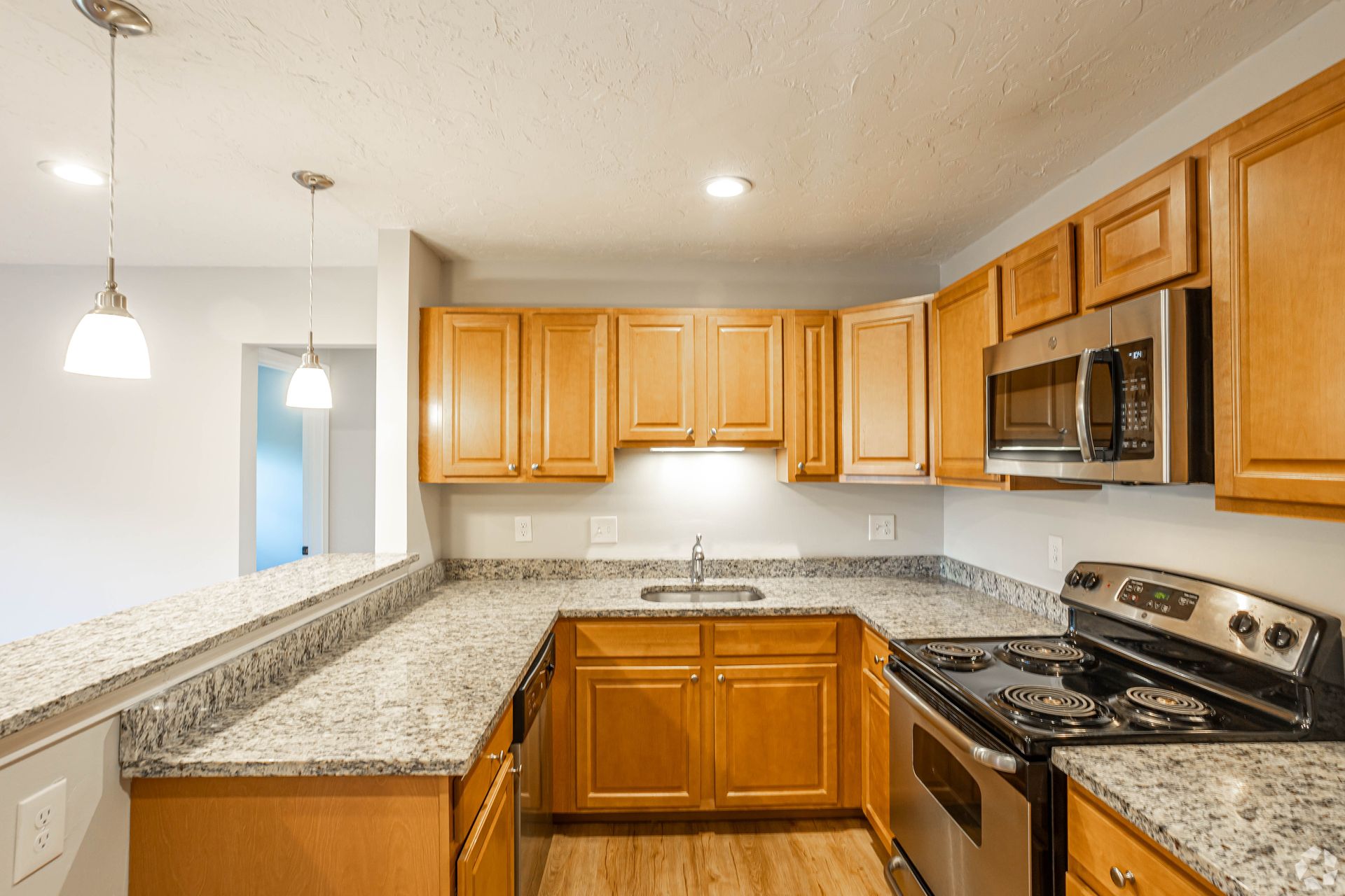 Apartment kitchen with granite countertops, wood cabinets, and breakfast bar at Waltham Overlook Apartments in Waltham, MA.