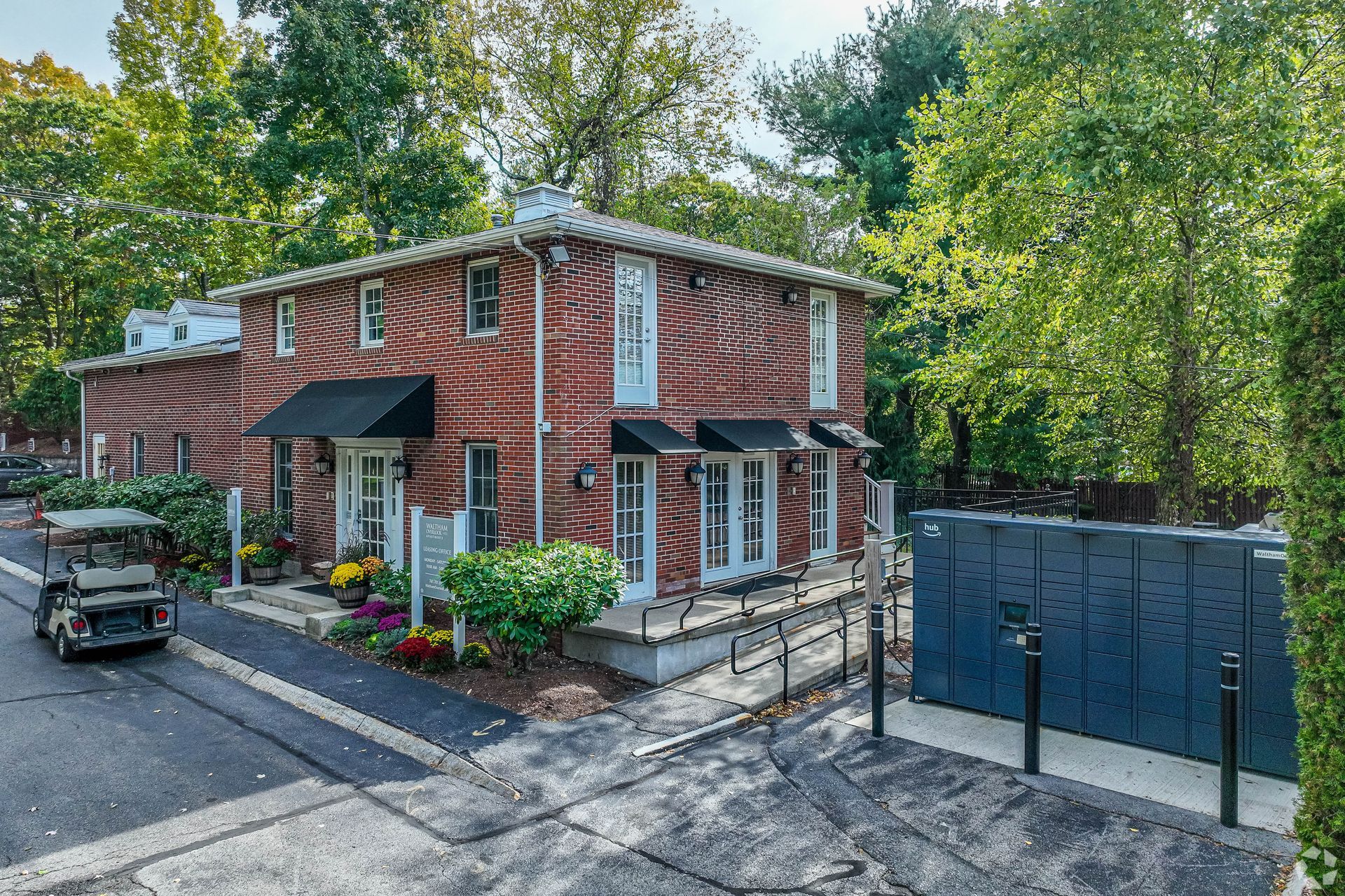 Leasing office exterior surrounded by trees and landscaping at Waltham Overlook Apartments in Waltham, MA.