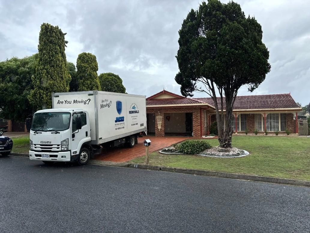 Moving Truck Parked in Front of a Brick House on a Cloudy Day — Forster Tuncurry Removals & Storage in Gold Coast, QLD