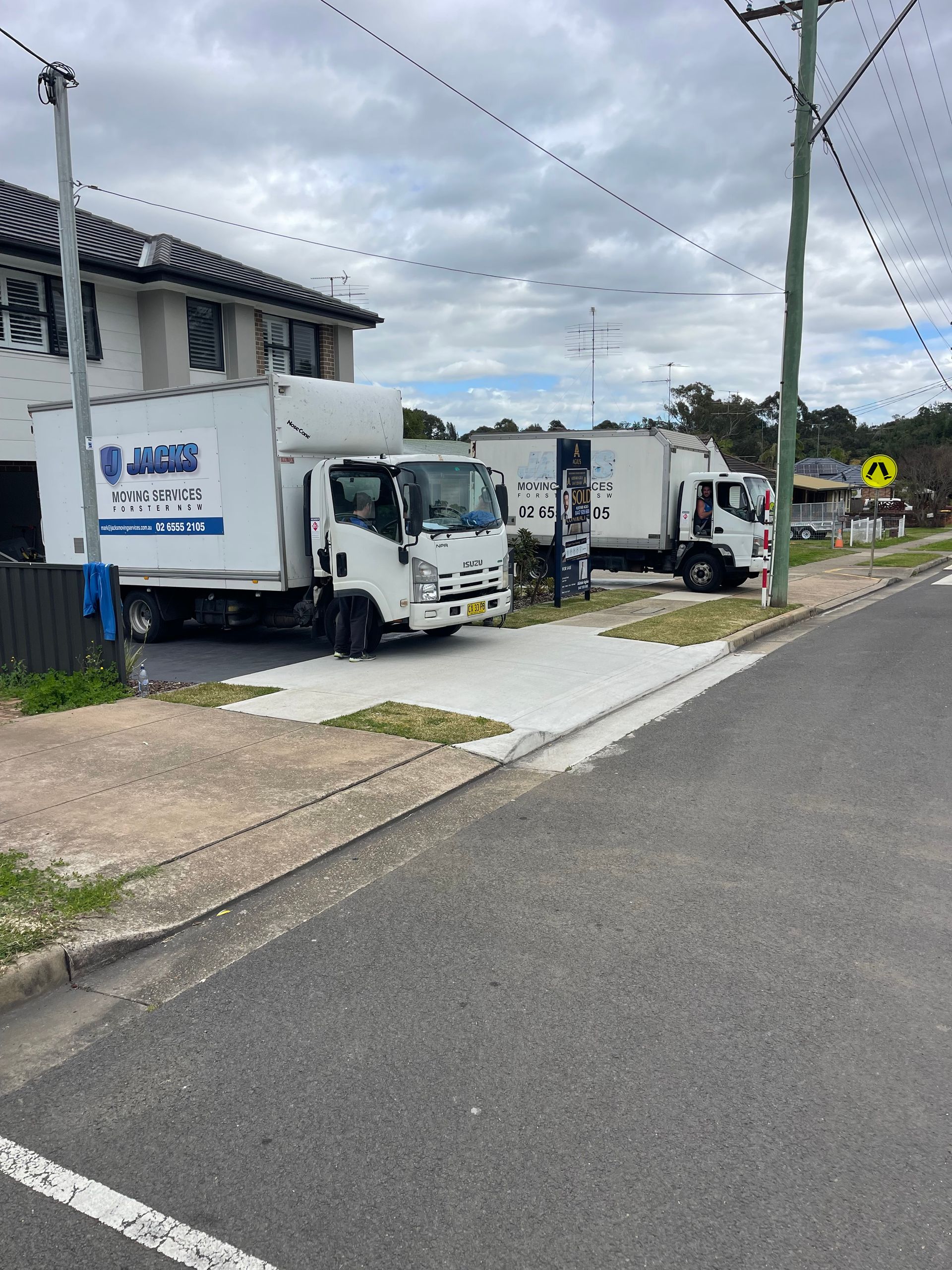 A Row of White Trucks Are Parked on the Side of the Road — Forster Tuncurry Removals & Storage in Tuncurry, NSW