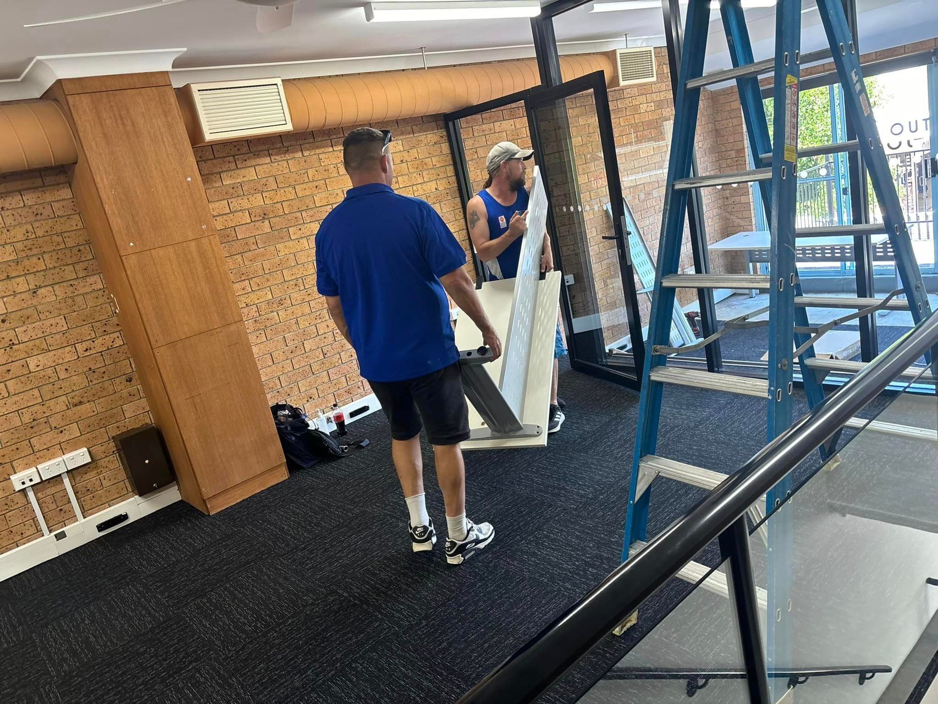 Two Men Are Carrying a Large Mirror in a Room — Forster Tuncurry Removals & Storage in Tuncurry, NSW