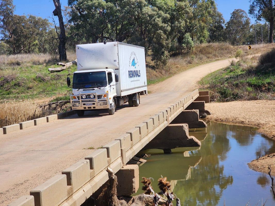 A White Truck Is Driving On A Bridge Over A Body Of Water — Forster Tuncurry Removals & Storage In Old Bar, NSW