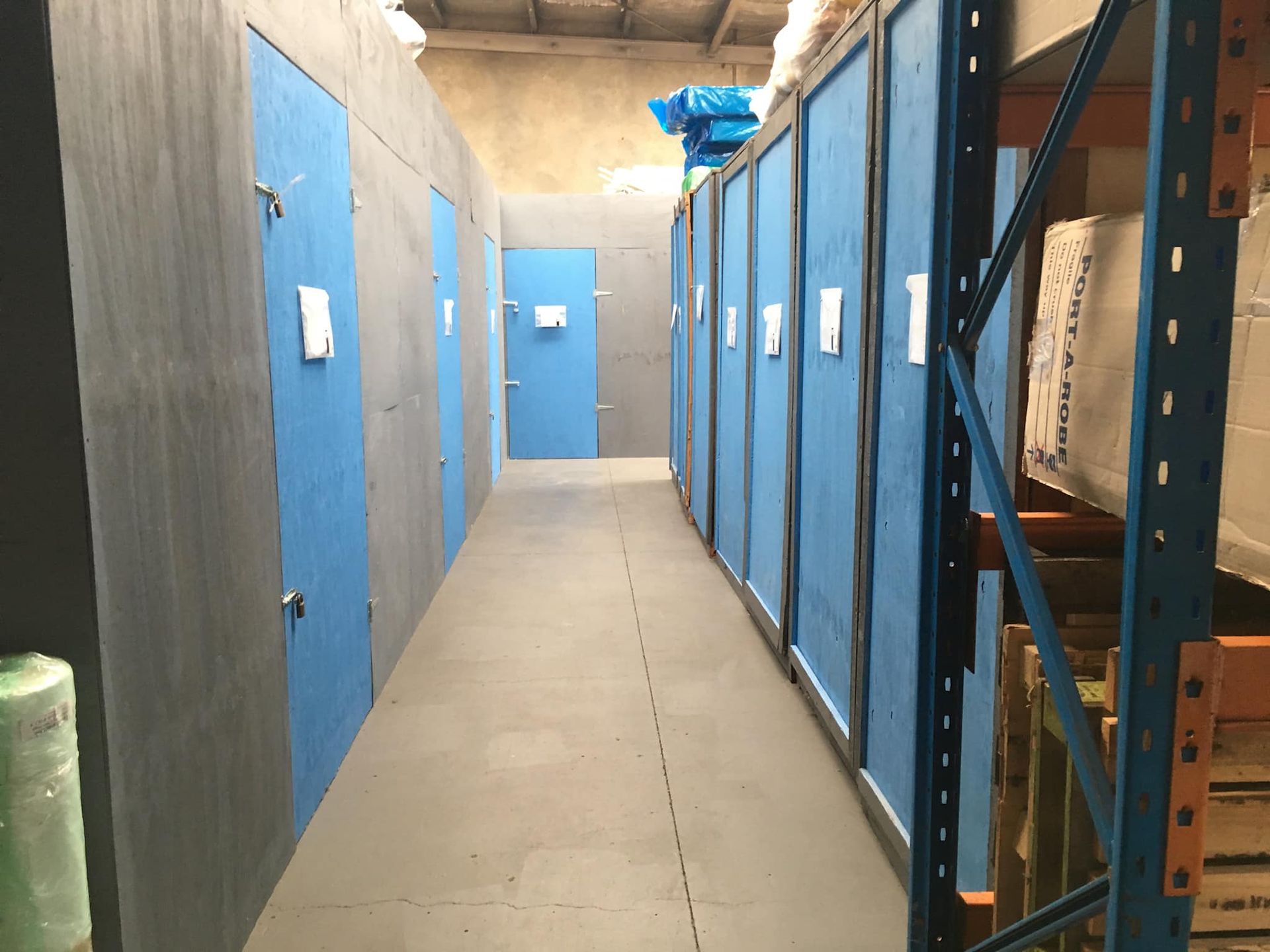 A Hallway in a Warehouse With Blue Doors and Shelves — Forster Tuncurry Removals & Storage in Tuncurry, NSW