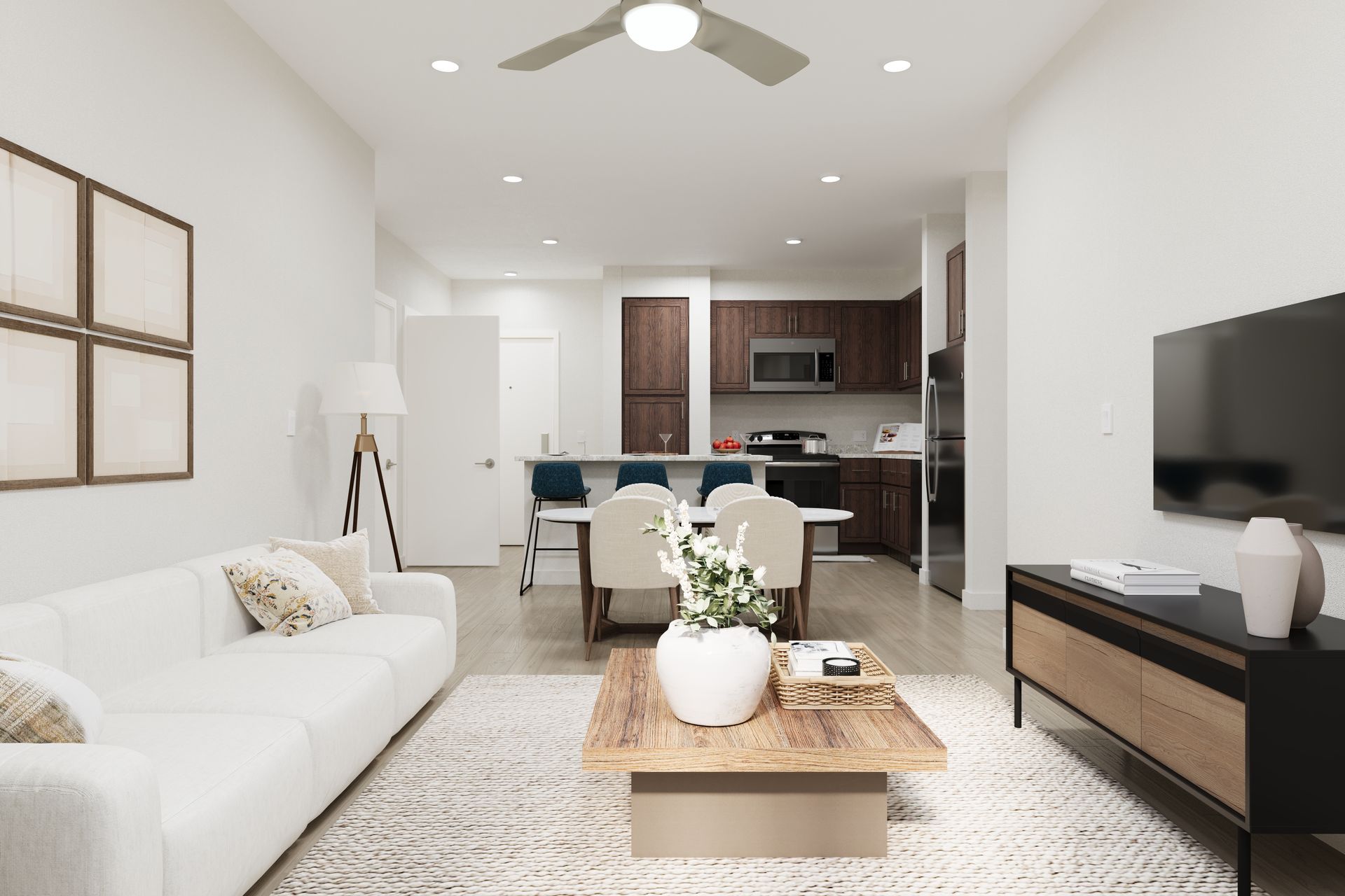 Bright modern living room with white sofa, coffee table, TV, and open kitchen in the background