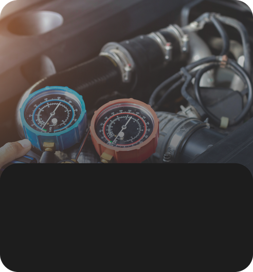 Blue and red manifold gauges held over car engine hoses and wiring | JB Auto Works