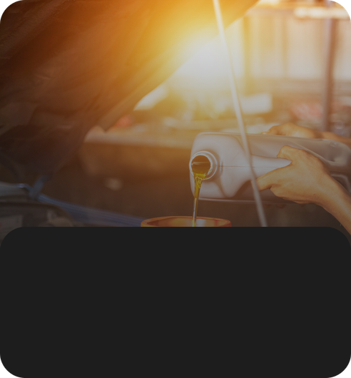 Car engine oil being poured under warm sunlight, with a hand holding the container. | JB Auto Works