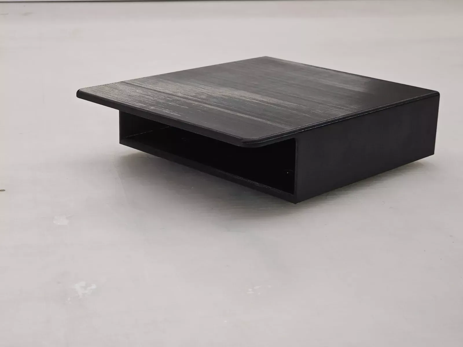 Black 3D-printed box with a hinged lid open, set against a white surface.