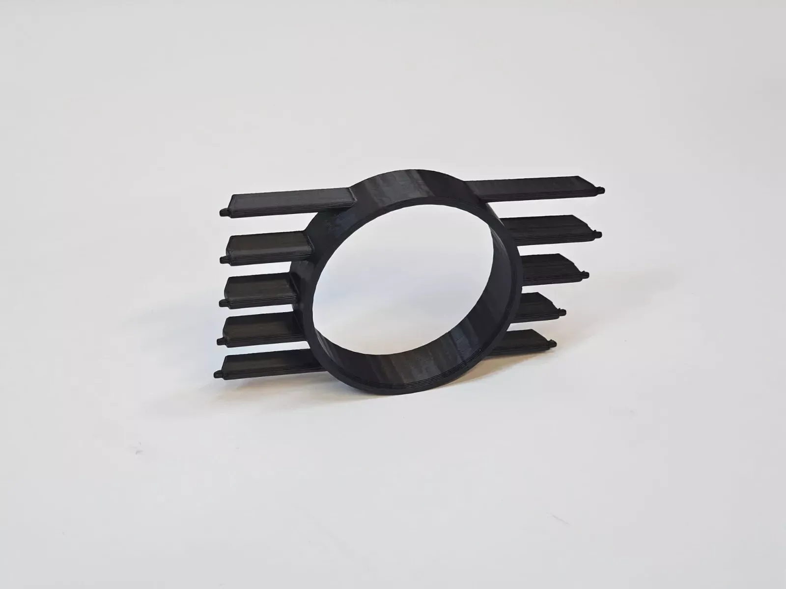 Black 3D-printed car fog light cover with horizontal slats and a central circular opening, against a white background.