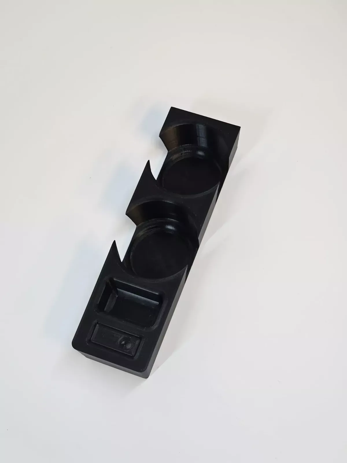 Black plastic car console insert with two cup holders and a small tray.