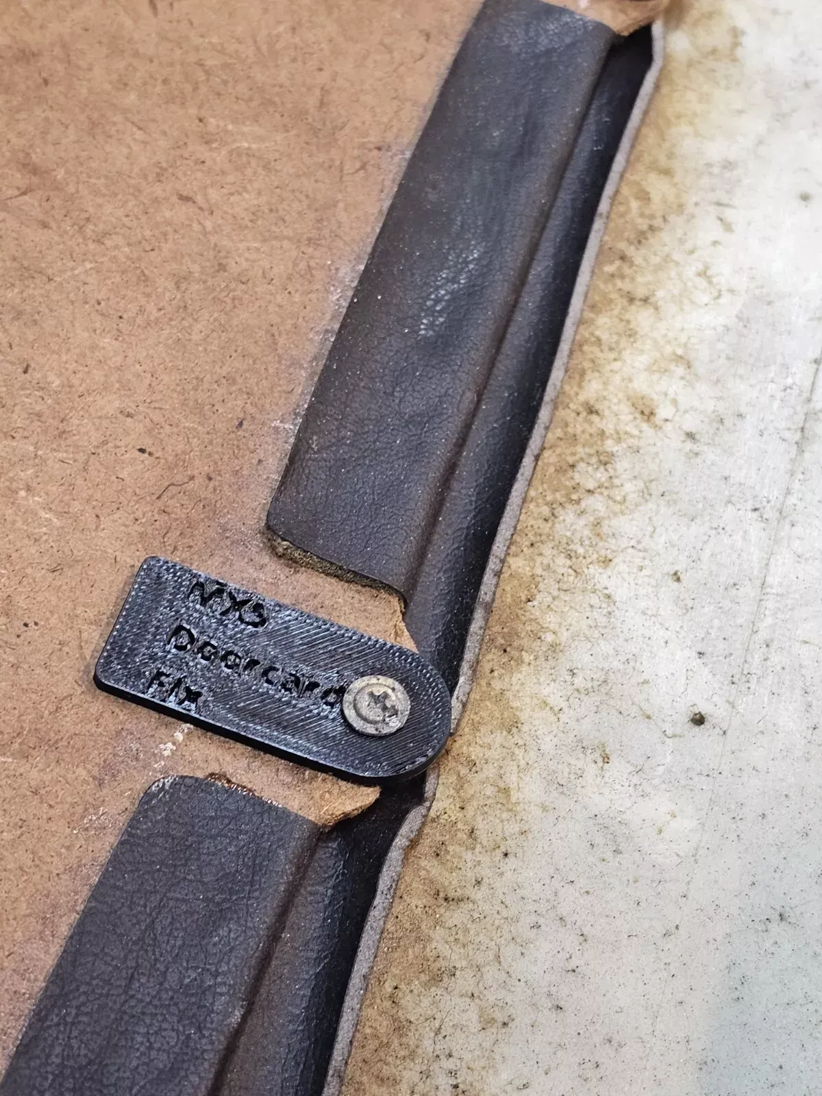 Black leather strap with a metal plate riveted to the brown backing, with text 