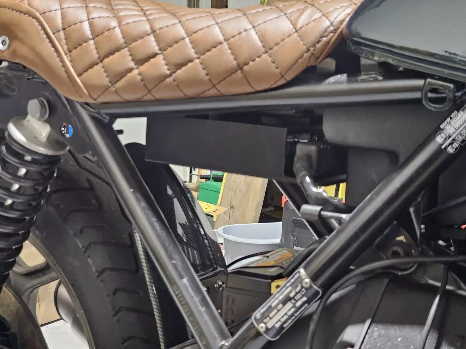 Black motorcycle frame with brown quilted seat.