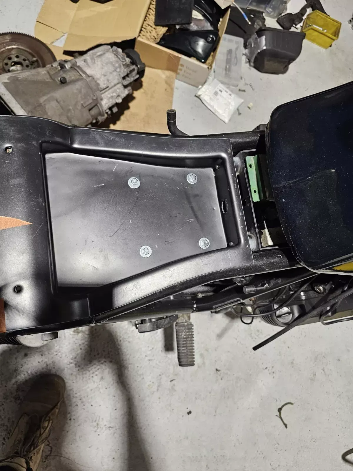 Black motorcycle frame with a black compartment and silver bolts.