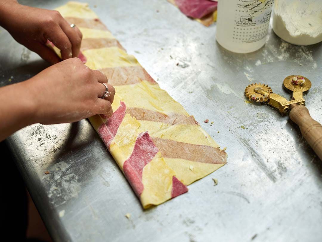 A person is cutting a piece of dough on a table.