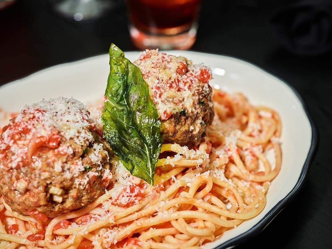 A close up of a plate of spaghetti and meatballs on a table.