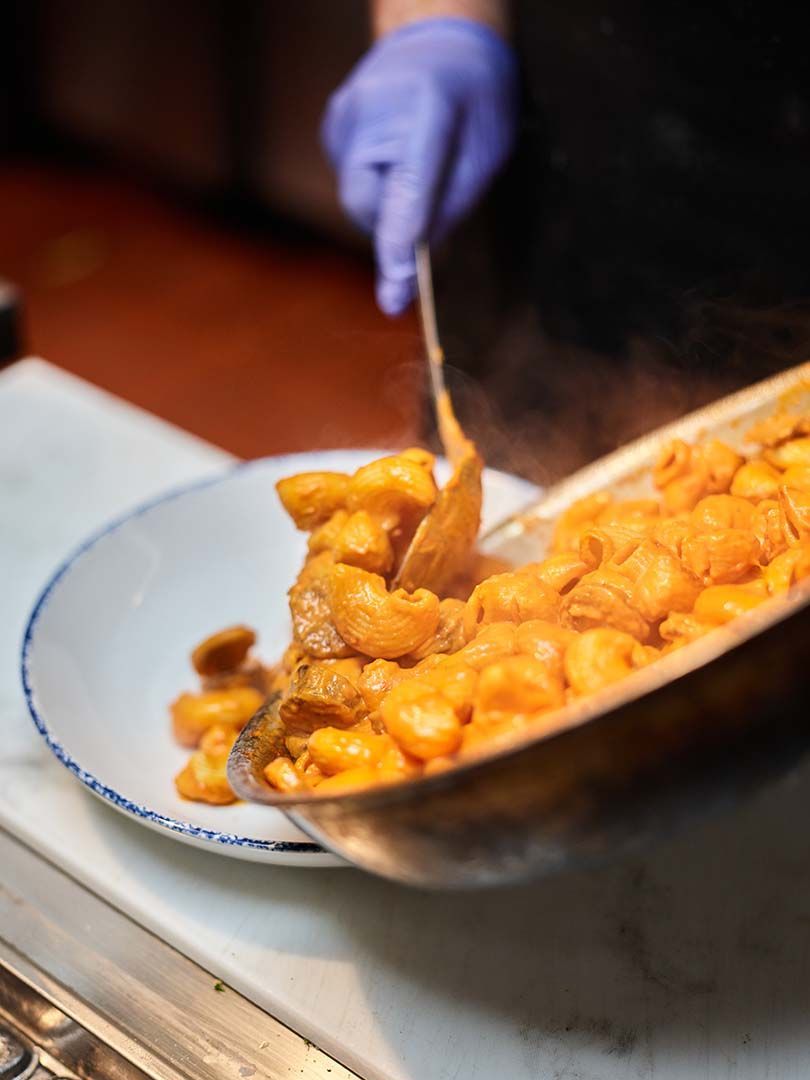 A person is pouring food into a plate on a stove.