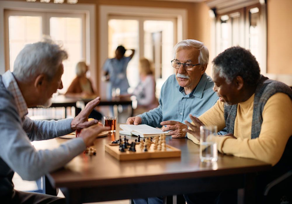 Friends playing cards at a bright table, smiling and laughing in a sunlit room