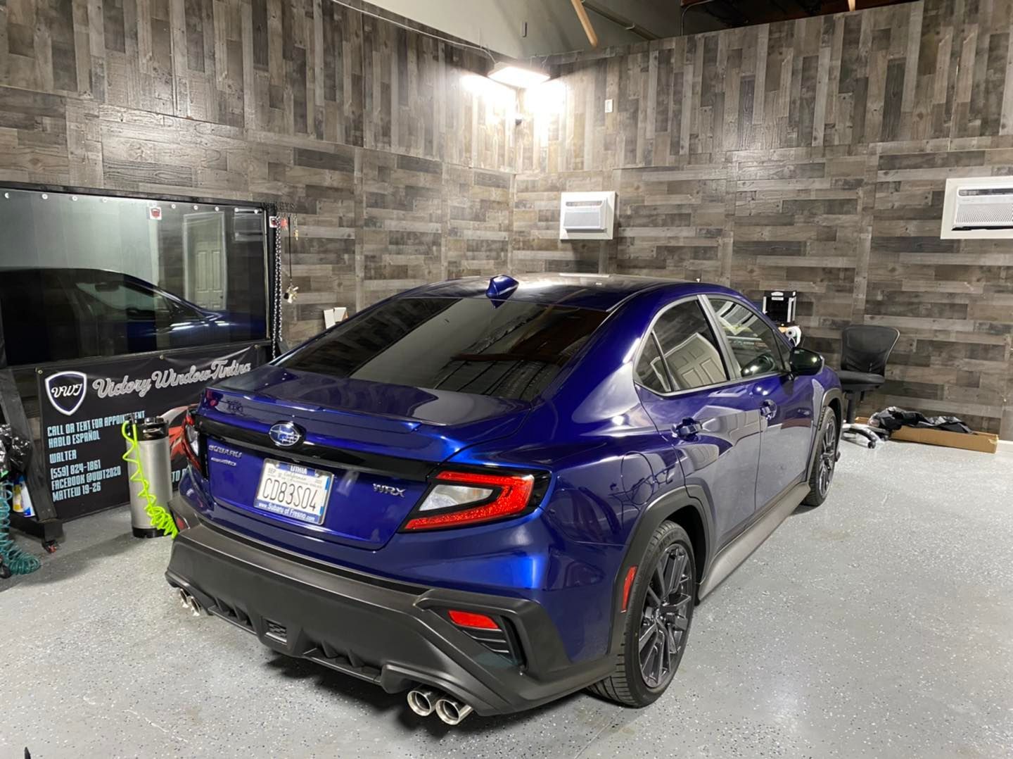 Blue sports sedan parked in a garage with gray stone walls and a car wash sign nearby
