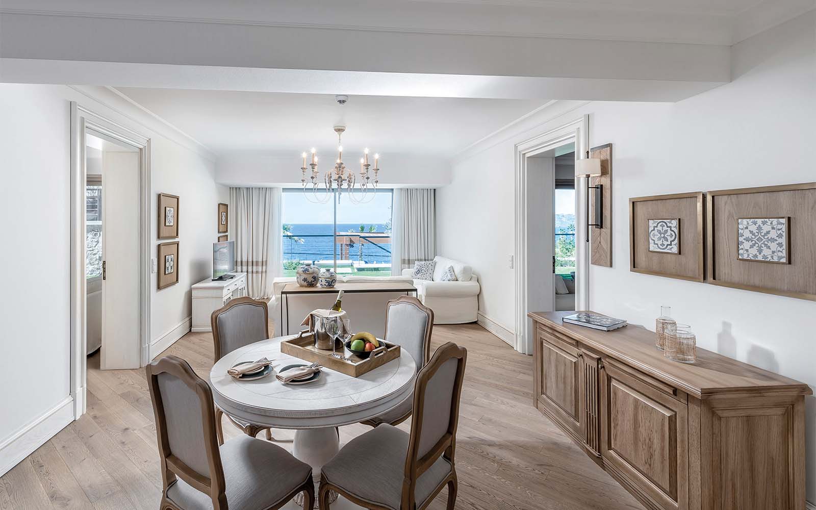 A living room with a dining table and chairs and a large window.