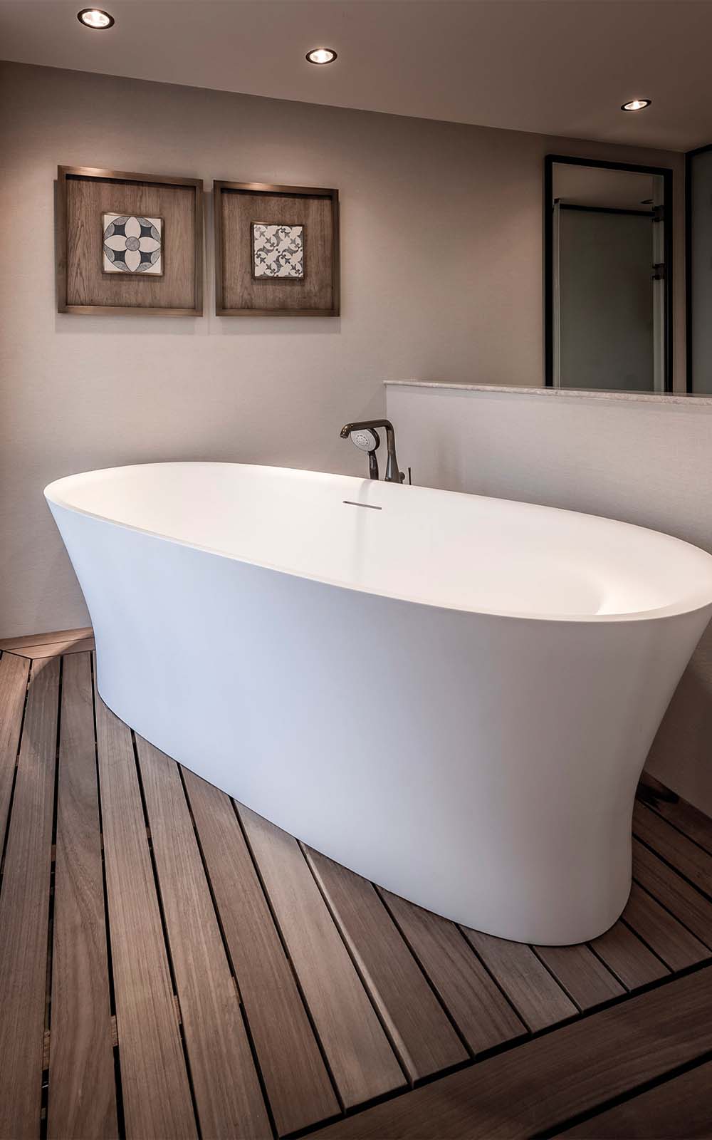 A white bathtub is sitting on a wooden floor in a bathroom.