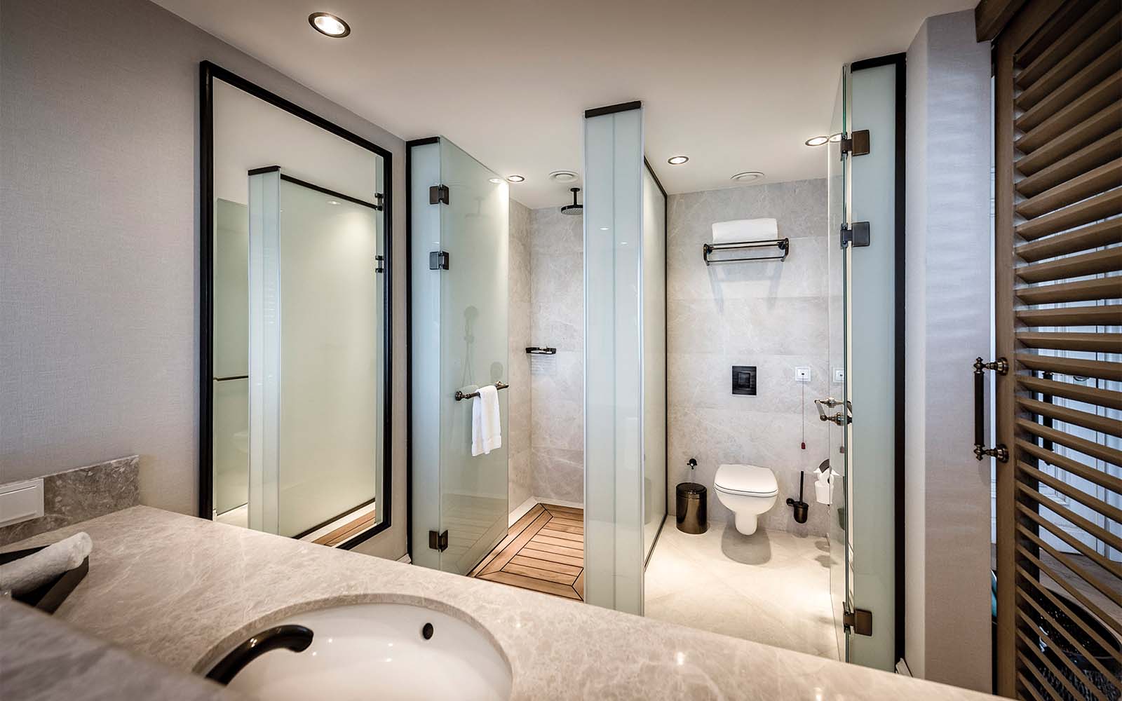 A bathroom with a sink , toilet , shower and mirror.