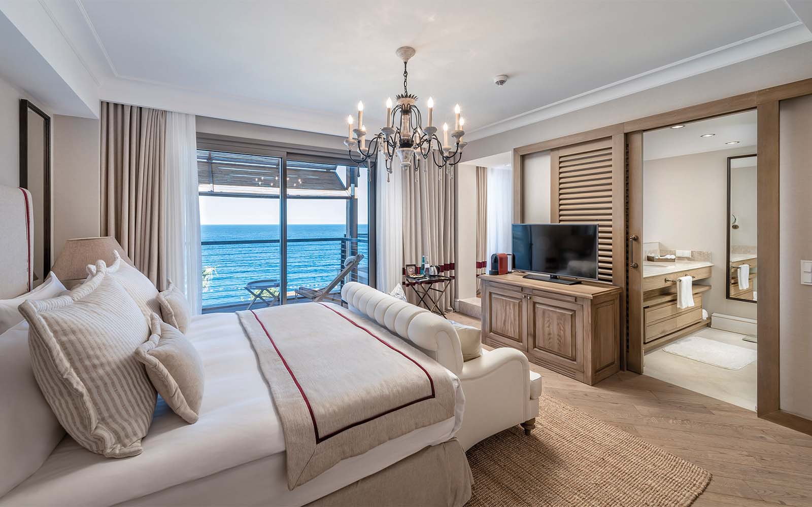 A hotel room with a large bed , couch , television and a view of the ocean.