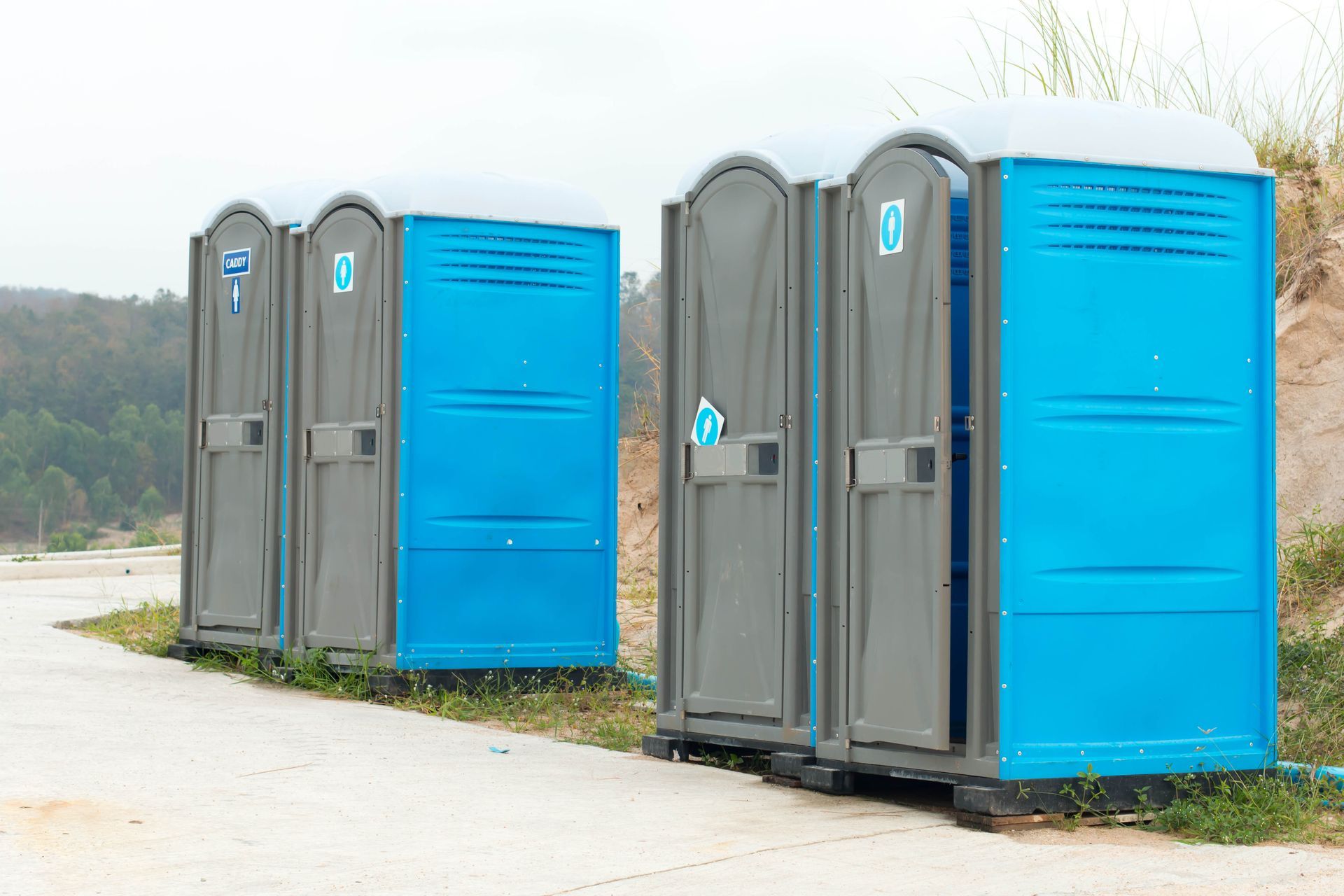 Row of blue and gray portable construction site restrooms lined up outdoors. Row of blue and gray portable construction site restrooms lined up outdoors.