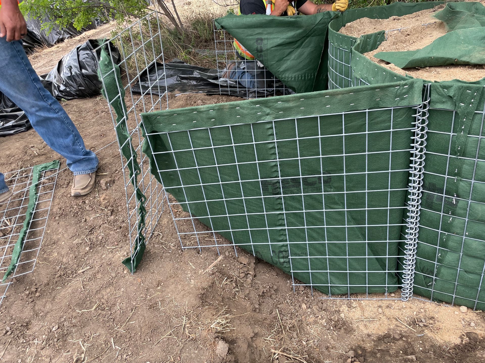 HESCO Flood Barrier being modified to tie into a levee to stop debris flows from flooding critical infrastructure