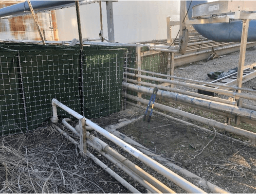 Preparing to plumb pipes through a HESCO floodwall