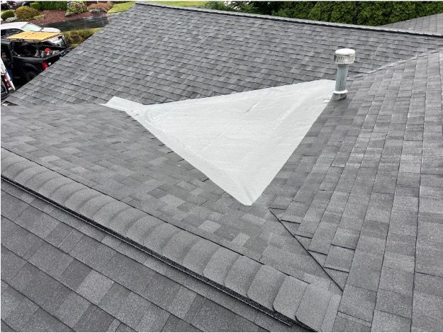 A dark, ribbed metal roof meets a white wooden gable wall with a small patch of peeling paint near the roofline.