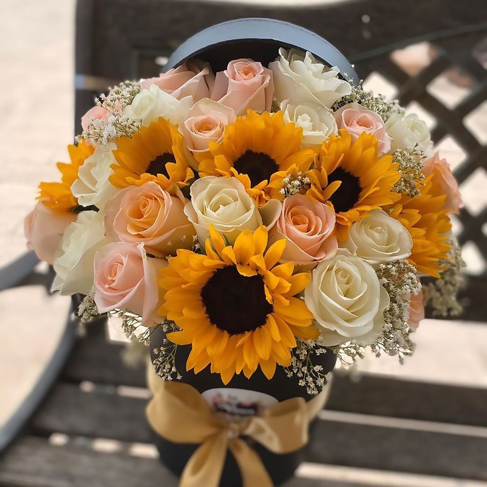 A bouquet of sunflowers and roses in a black box