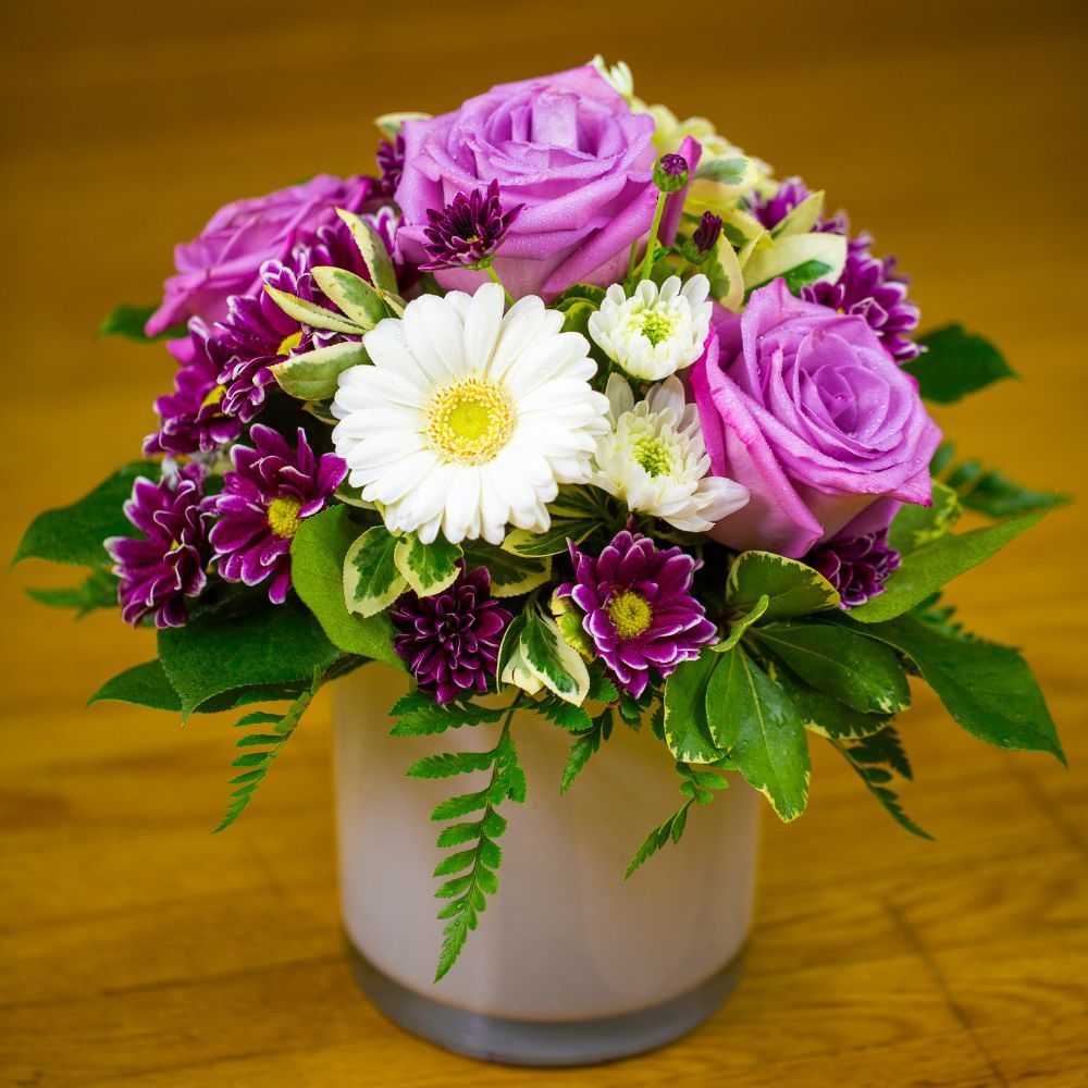 A vase filled with purple and white flowers on a wooden table