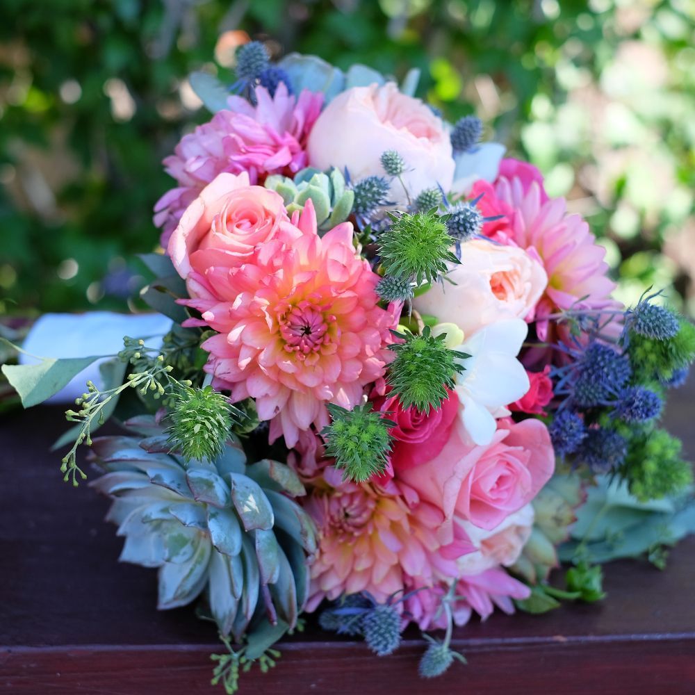 A bouquet of pink flowers sitting on a wooden table
