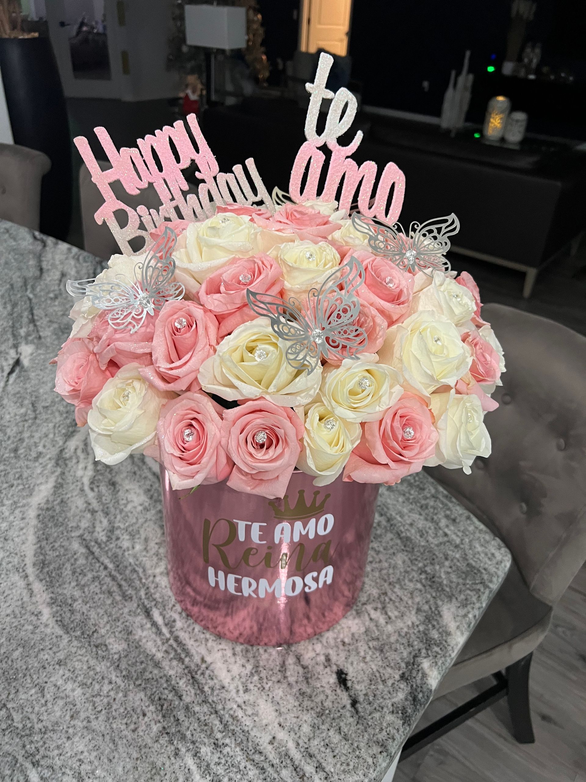A vase of pink and white roses with a happy birthday sign
