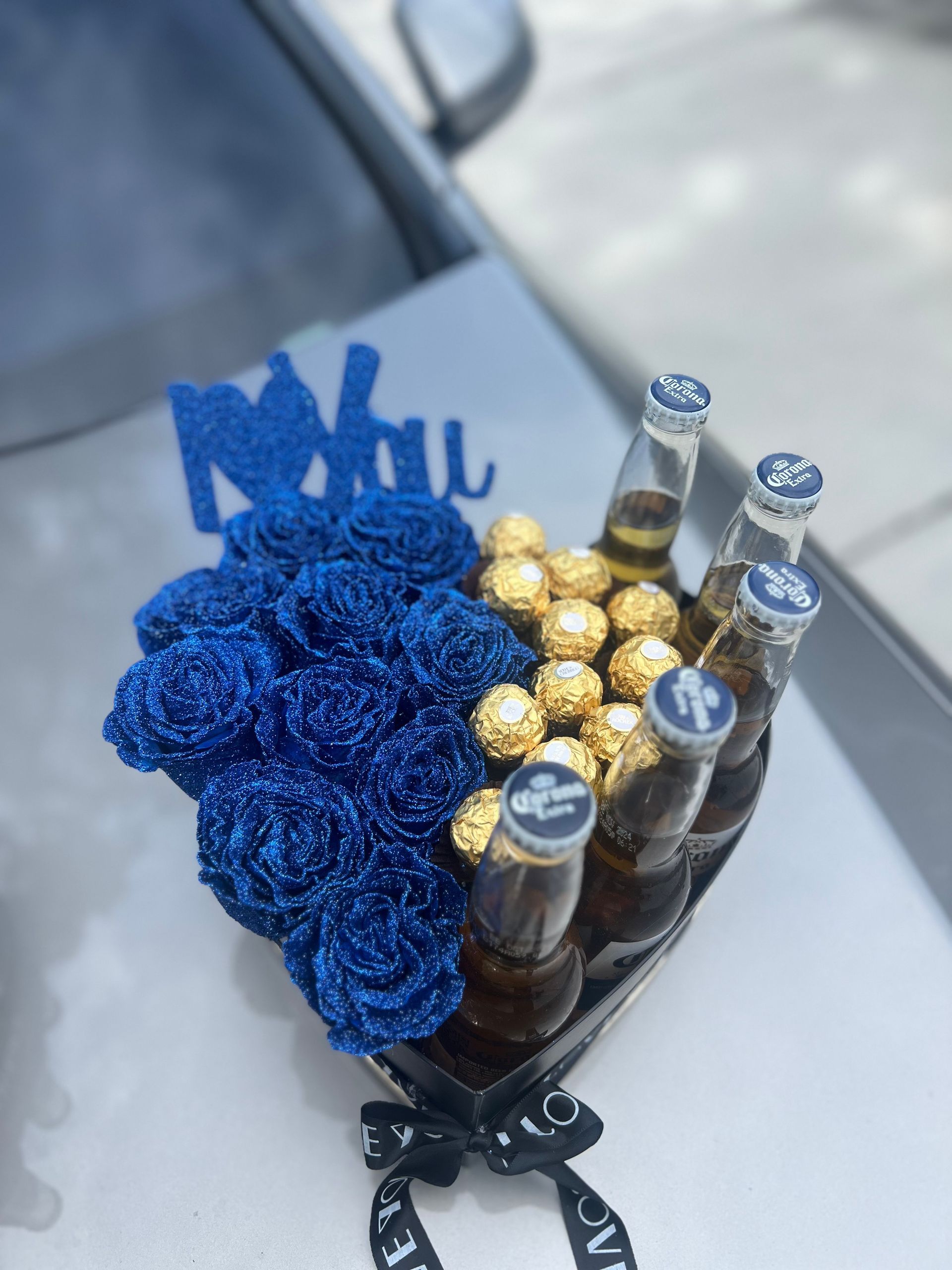 A heart shaped box with blue roses and beer bottles