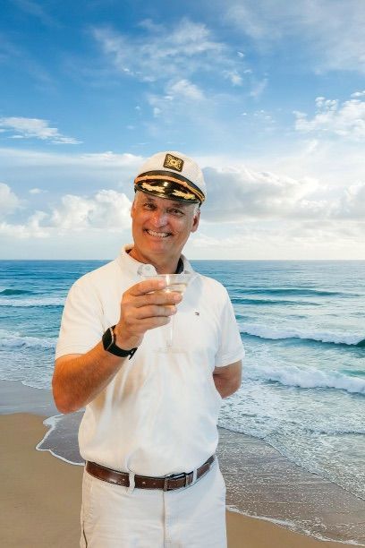 Man holding a fish on a beach with ocean waves and blue sky behind him