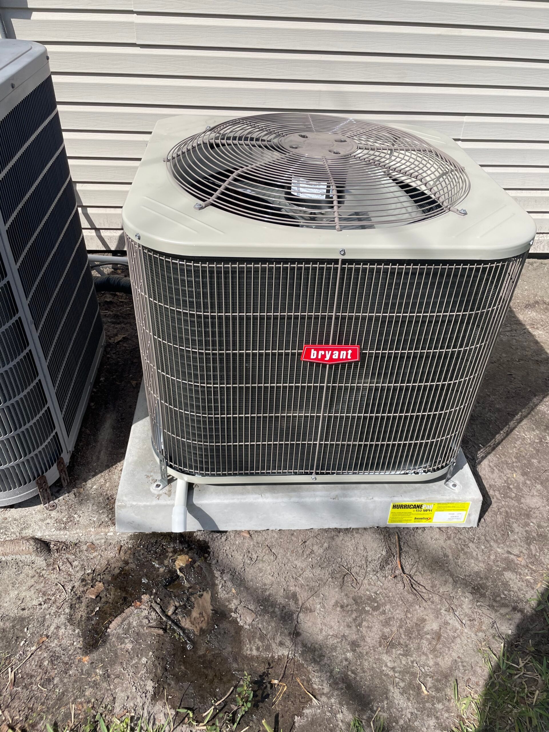 Air conditioning unit outside a house, with a fan on top.