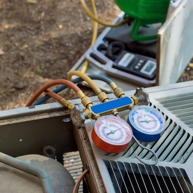 AC unit with hoses and gauges attached for servicing.