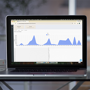 Laptop displaying a blue analytics line chart on a web dashboard in a browser window