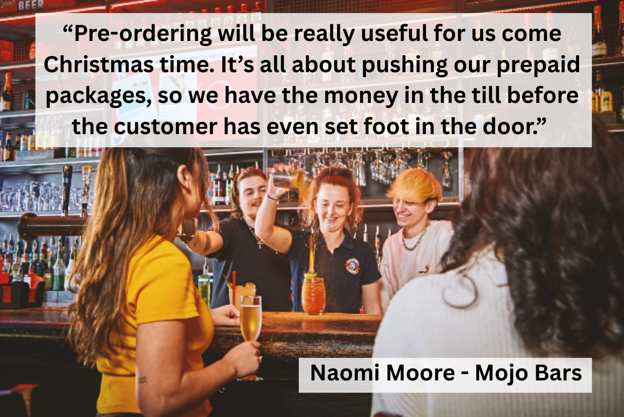 A waiter takes orders using an iphone from people sat in a beer garden 