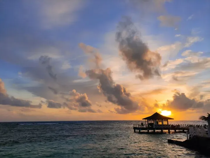 Atardecer sobre el mar de San Andrés con lancha en el horizonte, paisaje para disfrutar cerca de hoteles en San Andrés cerca a la playa.