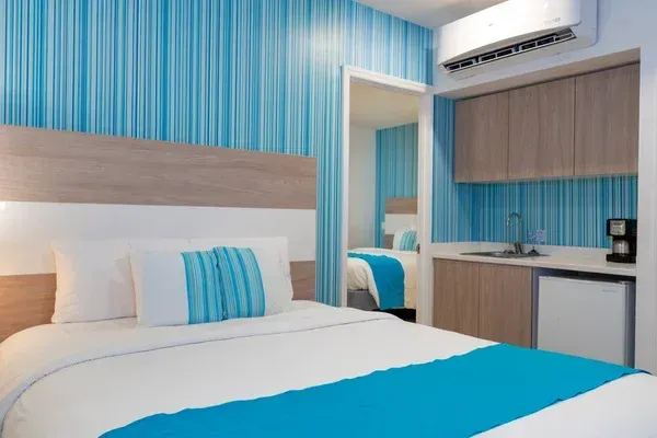 Modern room with double bed, blue-toned décor, and integrated kitchen, ideal for staying in San Andrés