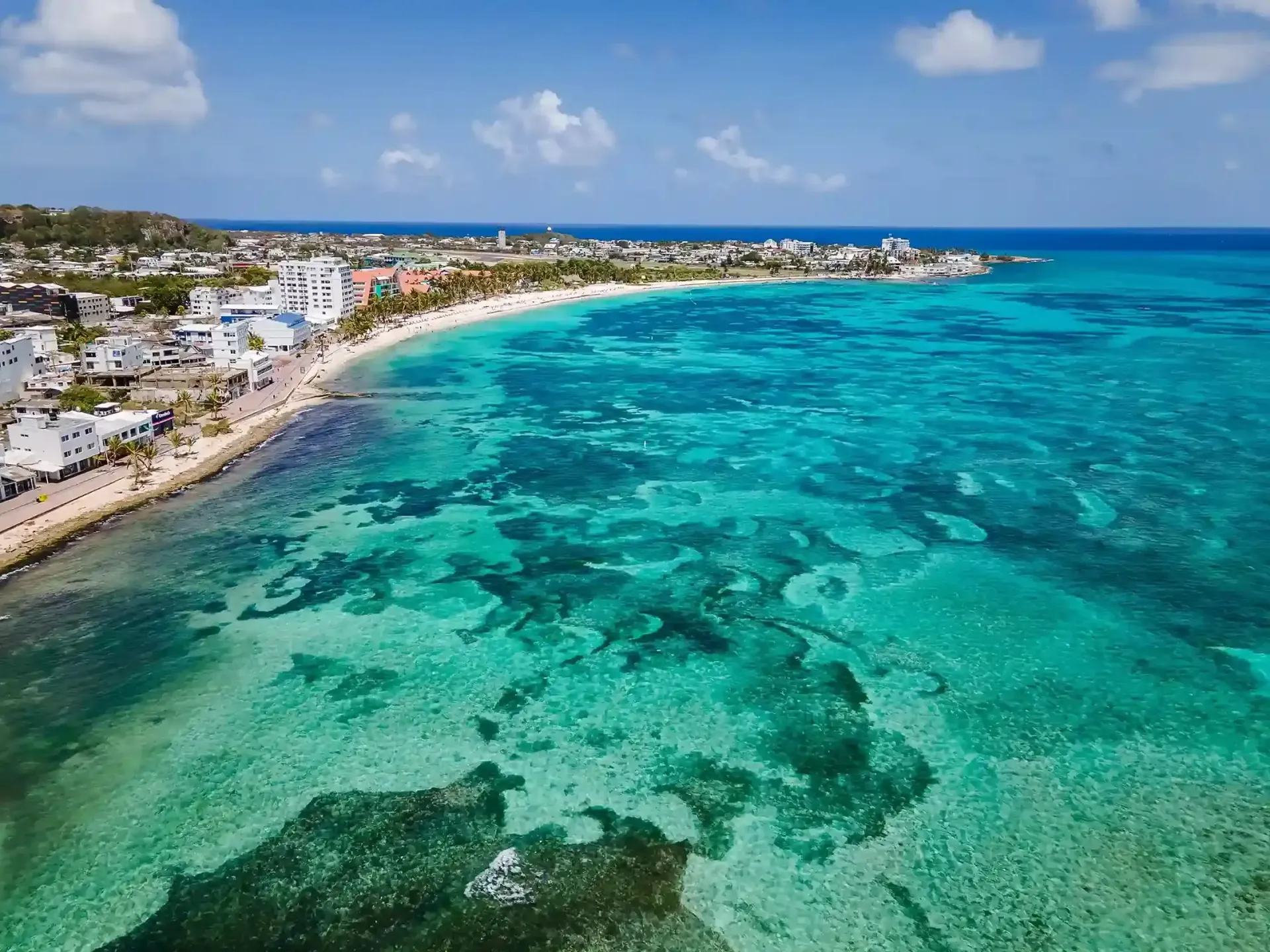 Maleta de playa y bebida frente al mar en San Andrés, ambiente ideal para vacaciones de descanso.