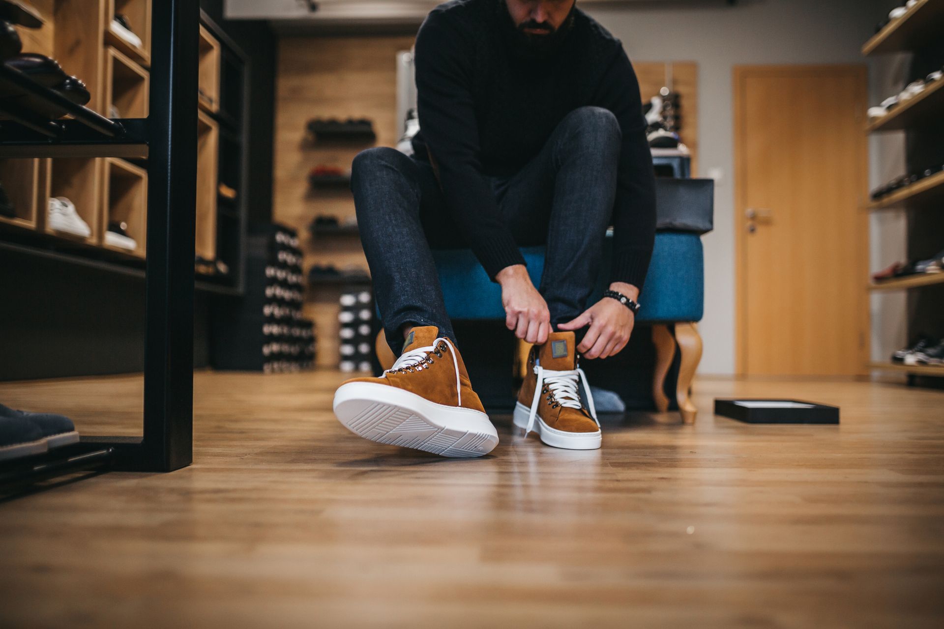 Un uomo è seduto su una sedia e si sta allacciando le scarpe in un negozio di scarpe.