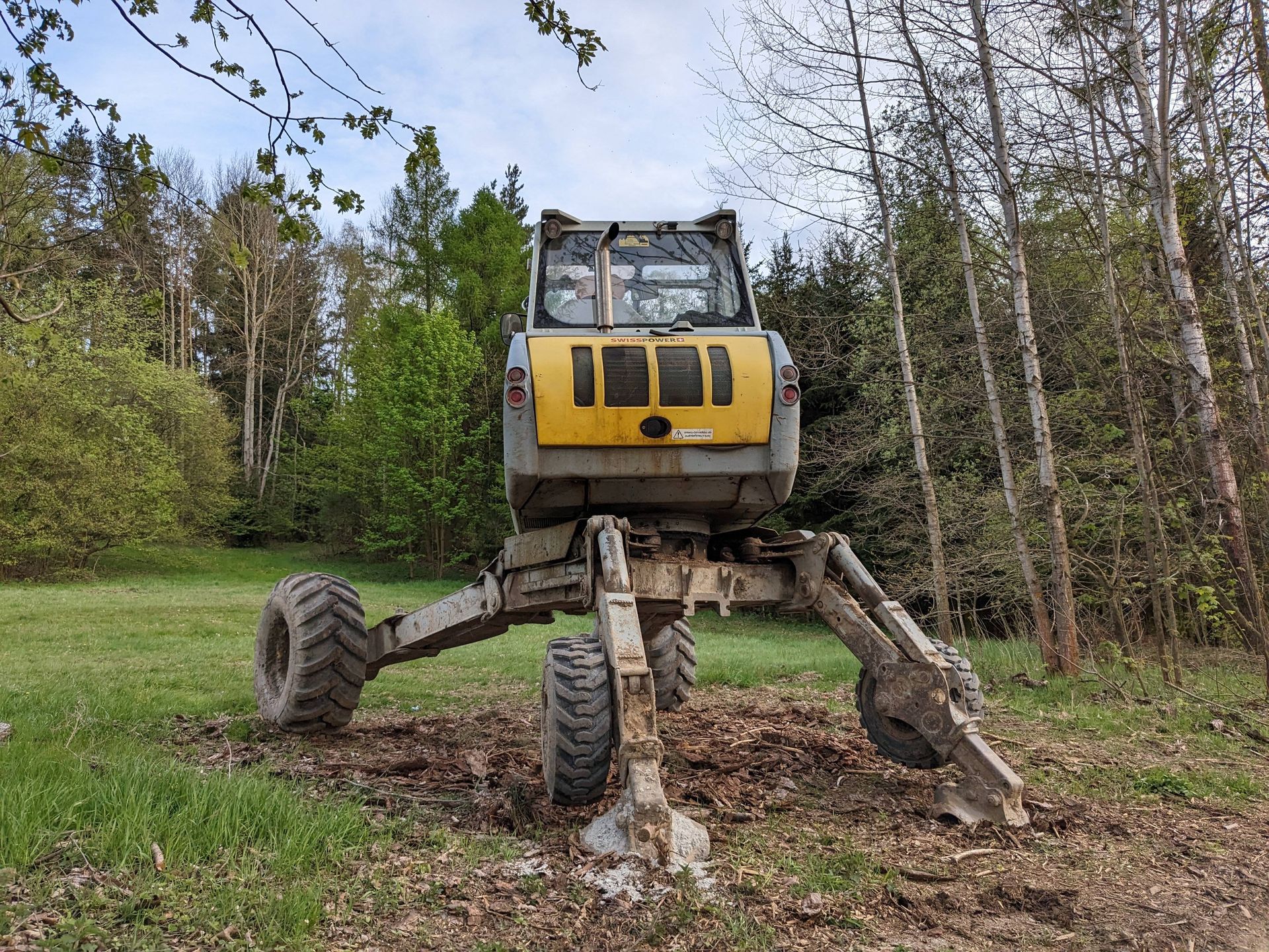 A yellow excavator is sitting in the middle of a field.
