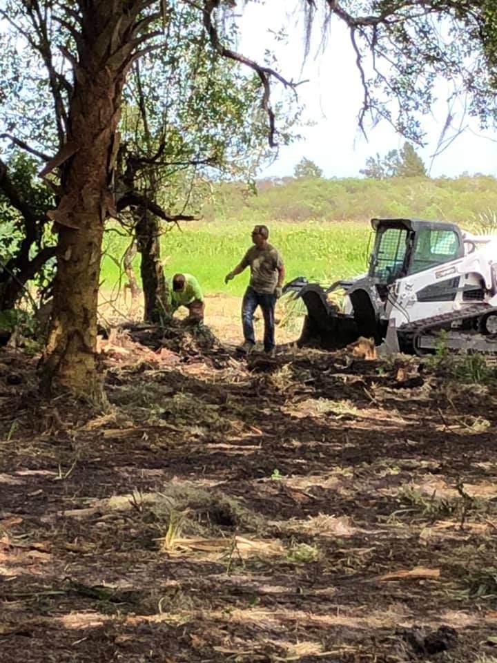 A man is standing next to a bulldozer in a field.