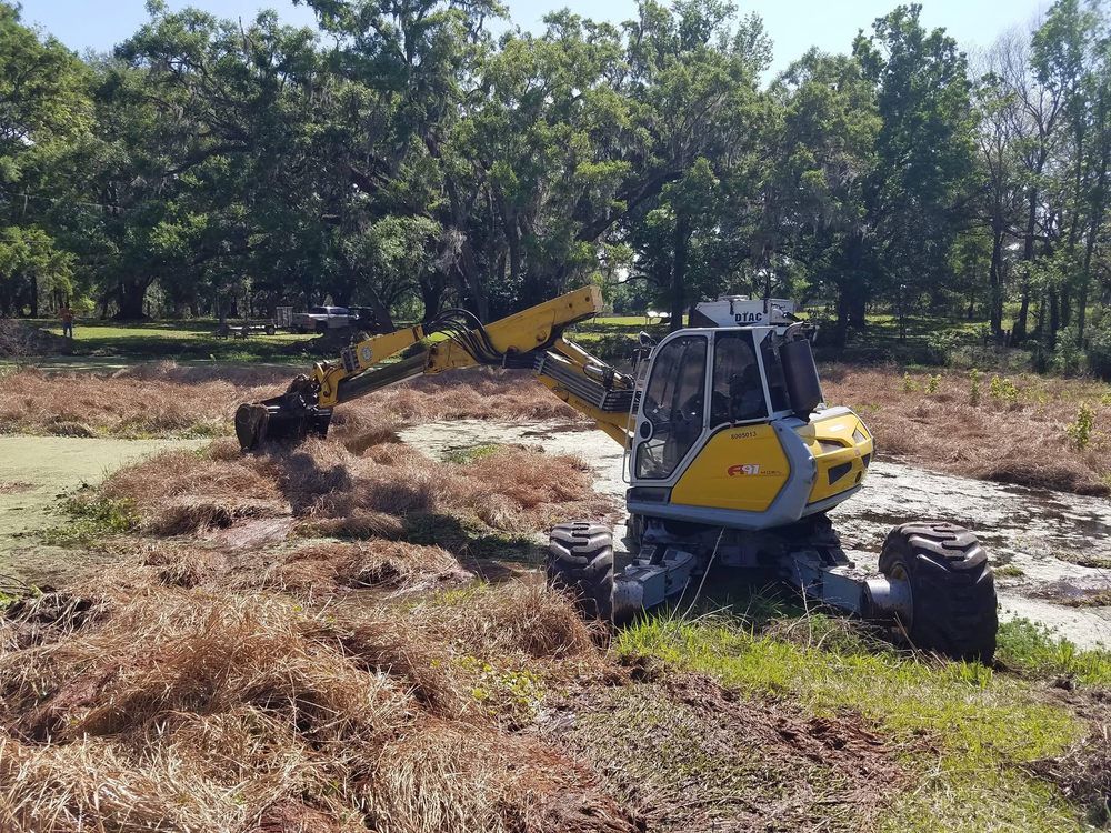 A yellow excavator is sitting in the middle of a field.