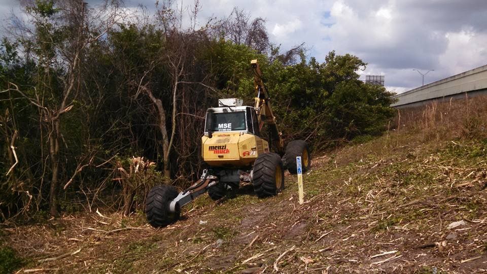 A large yellow excavator is driving down a dirt road.