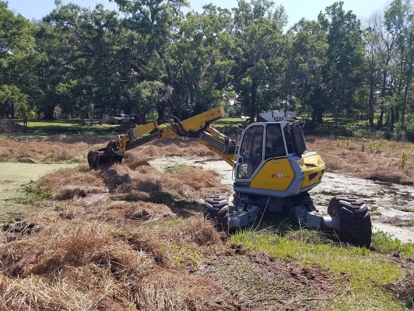 A yellow excavator is working in a field.