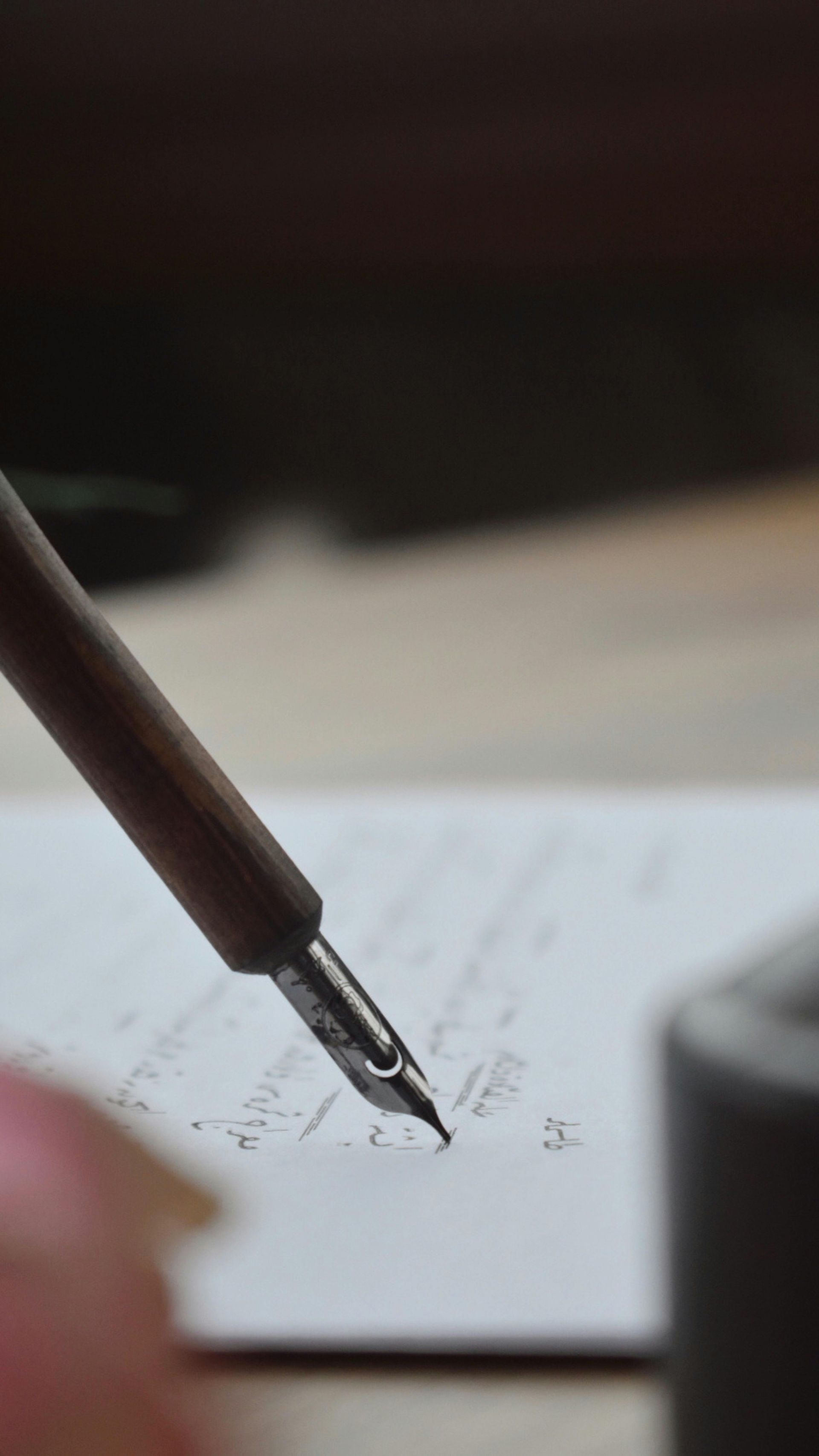 Close-up of a fountain pen writing on a lined notebook page with blurred background